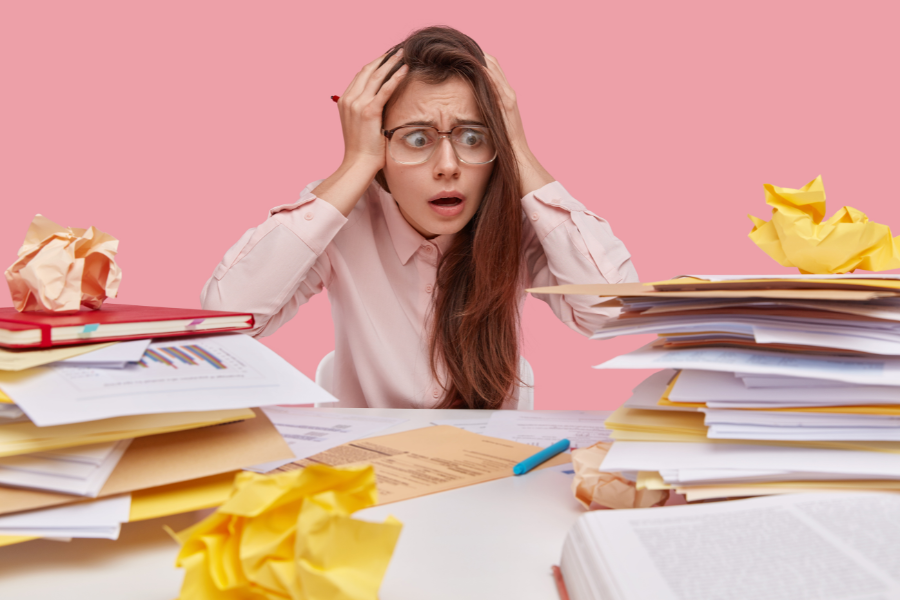 Femme débordée par ses piles de paperasse, ne sait plus où donner de la tête.